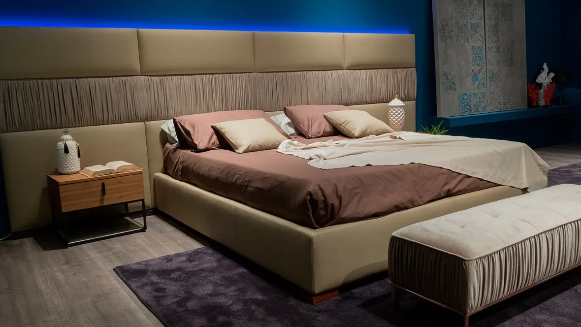 Letto con testiera modulare e morbida in cui le superfici sono scandite dall’alternarsi di rivestimento liscio e plissettato Infinity di Novaluna